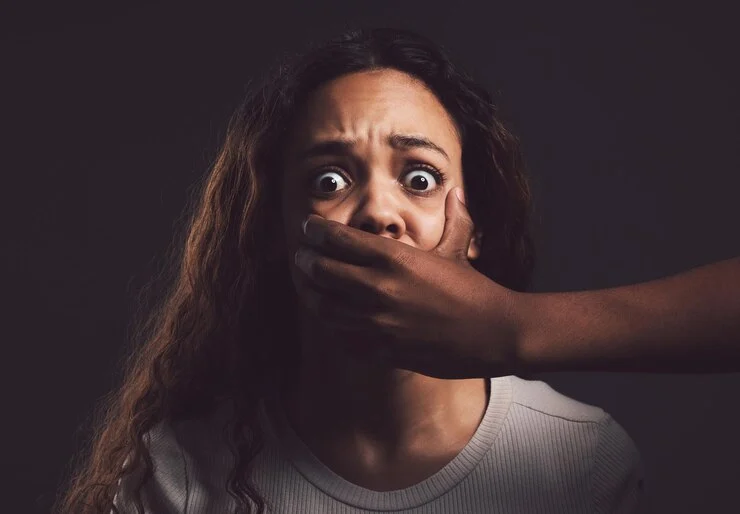 A woman silenced by a man’s hand symbolizing gender-based violence, used to highlight the importance of Monitoring and Evaluation in GBV programs