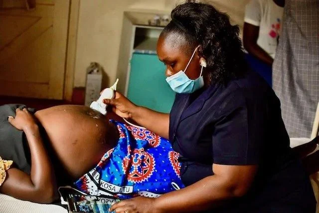 Healthcare worker checking a pregnant woman's blood pressure during an antenatal care visit in Nigeria.